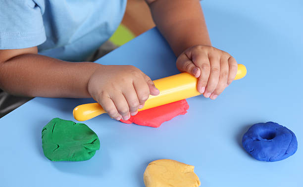 Child playing with modeling clay Children's hands with rolling-pin playing modeling clay. childs play clay stock pictures, royalty-free photos & images