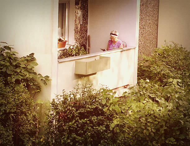 sênior mulher lendo um livro na varanda - plattenbau neubau apartment east germany - fotografias e filmes do acervo
