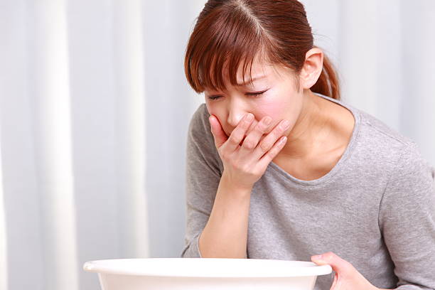 Young woman looking nauseous with hand over mouth Model is Japanese,mid twenties. food poisoning photos stock pictures, royalty-free photos & images
