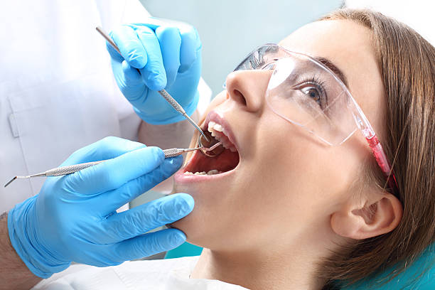 Overview of dental caries prevention Woman at the dentist's chair during a dental procedure dental light stock pictures, royalty-free photos & images