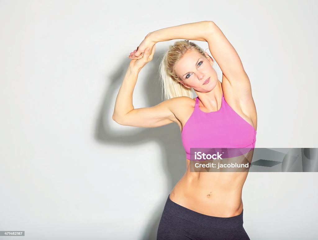 Beautiful Sporty Girl Stretching Studio shot of beautiful sporty girl stretching isolated on white. Blond Hair Stock Photo