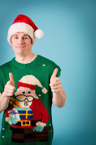 Man Thinks He's Cool Wearing Santa Hat and Ugly Vest Color image of a man wearing a Santa hat and an ugly Christmas vest with an "I'm cool!" expression on his face. christmas ugliness sweater nerd stock pictures, royalty-free photos & images