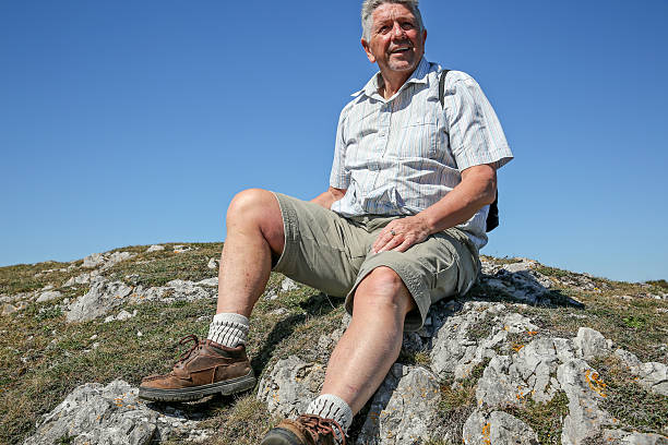 Mature man hiking in Wales sitting on coastal headland