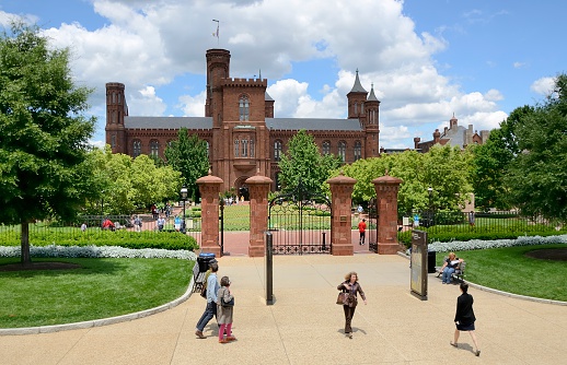 Washington DC, USA - June 5, 2012: People at the Smithsonian Institute in Washington DC on a sunny day with fluffy clouds partially casting the building in shade.