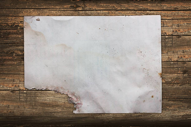 istock Damaged old paper ona dark wooden background 471488165