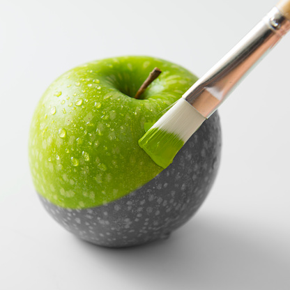 Painting a fresh green apple with paintbrush