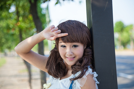 asian female in summer standing next to a pole