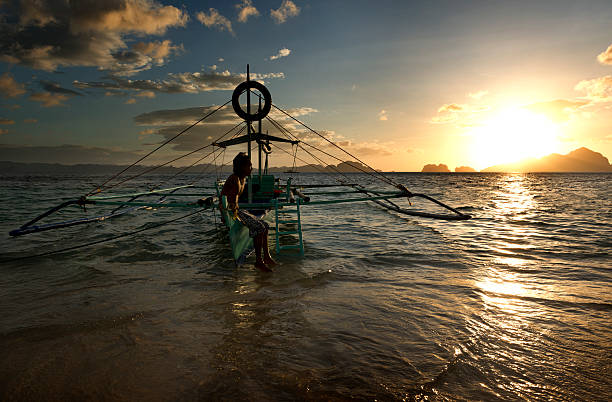 philippino con la sua tradizionale banca canoa con bilanciere imbarcazioni nelle filippine - nautical vessel philippines mindanao palawan foto e immagini stock