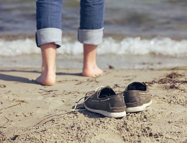 istock Man Leaving His Shoes Behind on the Sand 471492133