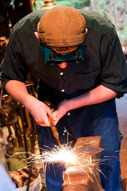 Fusion Welding Sparks fly as a young male artistic meatalworker "fusion" welds metal with an oxyacetylene torch.  "Fusion" is where two pieces are joined (melted together) without the addition of a filler rod. oxyacetylene stock pictures, royalty-free photos & images