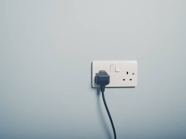 UK wall socket and cord on blue wall stock photo