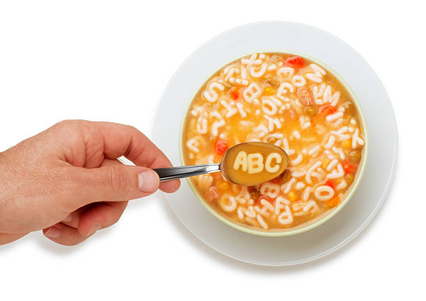 ABC Soup This is an overhead photo of a man scooping out of a bowl of Alphabet Soup with the message on the spoon spelling "ABC". There is a clipping path and the background is a pure white. alphabetical order photos stock pictures, royalty-free photos & images