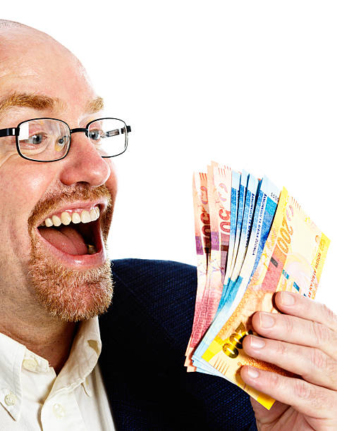 istock Overjoyed mature man smiles down at South African banknotes 471496205