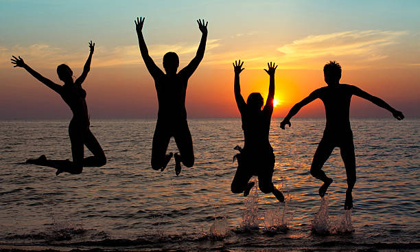istock silhouette of jumping people on sunset background 471496549