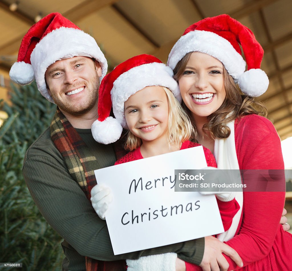 Happy family wearing santa hats and holding ""Merry Christmas: sign Happy family wearing santa hats and holding "Merry Christmas: sign Child Stock Photo