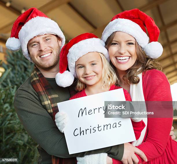 Happy Family Wearing Santa Hats And Holding Merry Christmas Sign Stock Photo - Download Image Now