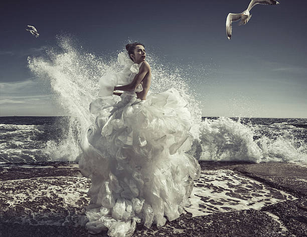 women in plastic bag dress at sea wave background