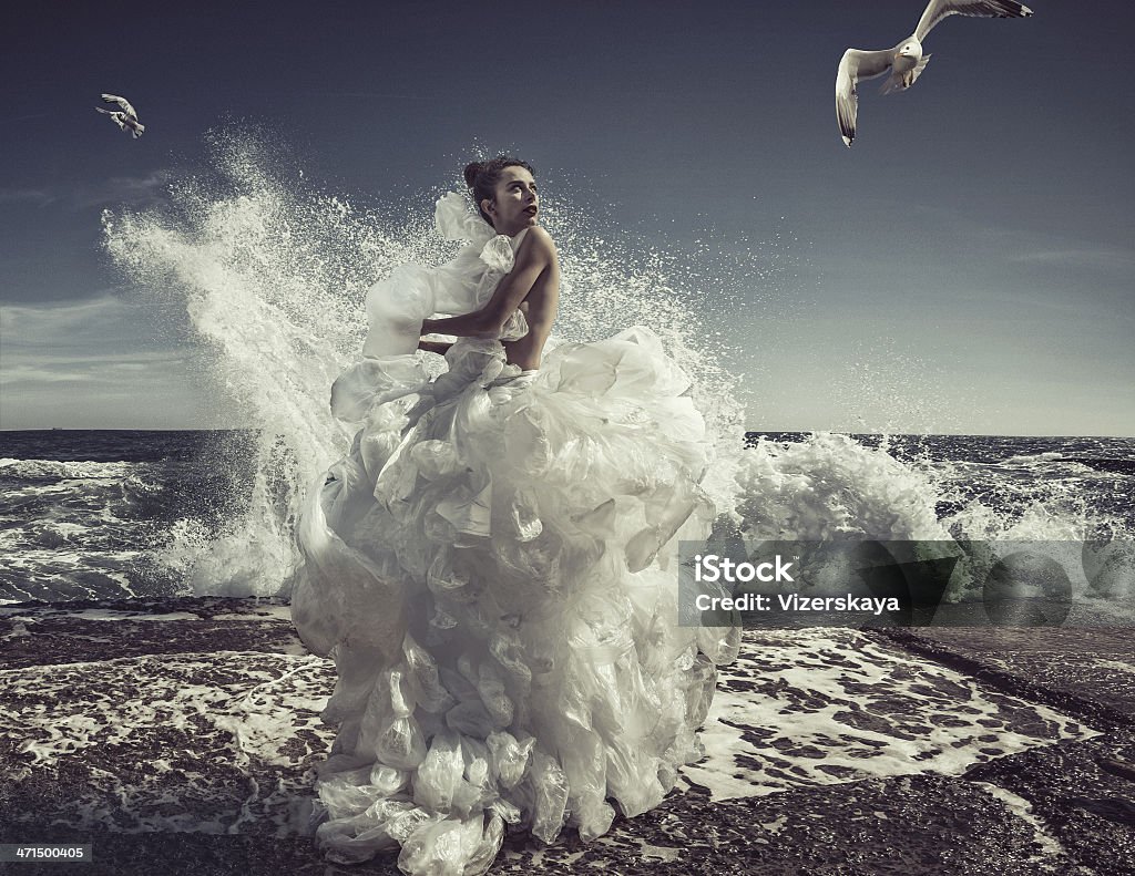 women in plastic bag dress women in plastic bag dress at sea wave background Fashion Stock Photo