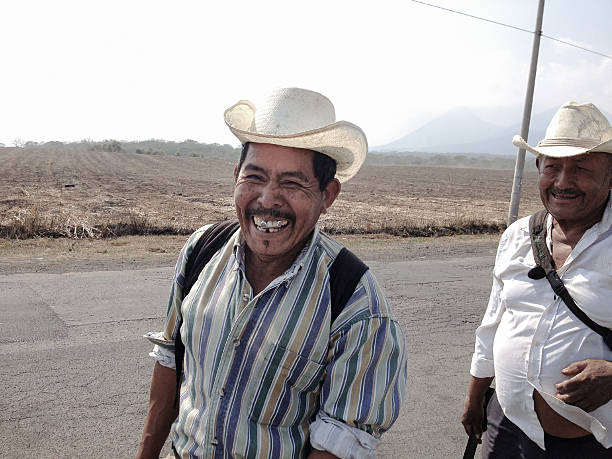 San Isidro, El Salvador - March 11, 2013: A pair of sugar cane farmers walk along the road in a joyful manner.