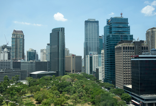 Manila, Philippines - April 17, 2013: Office view from the 14th level in a building in the financial district of Makati City. The peaceful and green Ayala triangle surrounded by skyscrapers and traffic.