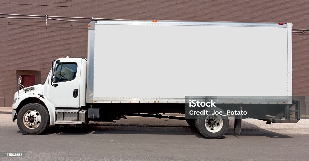 White DeliveryTruck White delivery truck parked against mauve brick building....Yes, mauve. Copy space on side panel. Horizontal. Brick Stock Photo