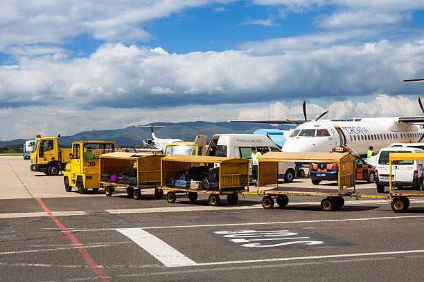 Zagreb, Croatia - April 28, 2013: Airport trucks handling baggage on the Pleso Airport tarmac in Zagreb, Croatia, in front of a grounded fleet of Croatian Airlines