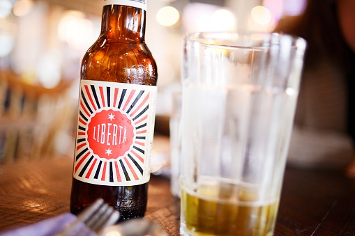 London, England - April 27, 2013: A bottle of Liberta beer at 'Jamie's Italian' restaurant at London Gatwick Airport. The beer was created by the british chef and media personality Jamie Oliver in conjunction with the award winning beer maker Freedom Brewery.