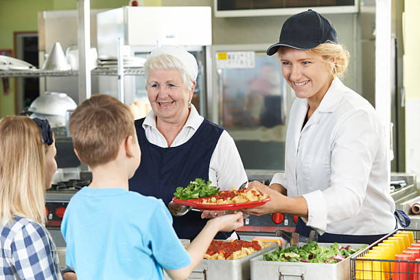 Pupils In School Cafeteria Being Served Lunch By Dinner Ladies Pupils In School Cafeteria Being Served Lunch By Dinner Ladies cafeteria worker photos stock pictures, royalty-free photos & images