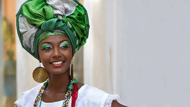 Baiana, Brazilian woman of African descent, smiling, wearing traditional attire in Pelourinho, Salvador, Bahia, Brazil.