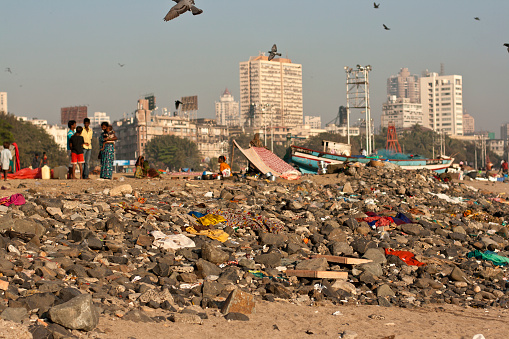 Mumbai, India - January 6, 2012: a camp of destitute families along the Marine Drive, Mumbay, living over trash and debris. Many of them try to make a living by fishing in the polluted Gulf