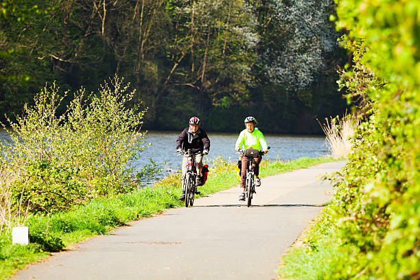 Essen, Germany - May, 1st 2013: A senior couple is cycling along river Ruhr in south of Essen in district Kettwig in morning spring sunshine.