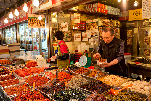 Seoul, South Korea - April 27, 2013: Vendors are selling kimchi at local market. Kimchi, the staple Korean food, is long-term fermented vegetables served as a side dish. the Gwangjang Market is the nation's first market and also a popular tourist destination. 