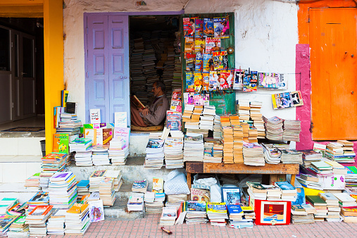 Meknes, Morocco- February 16, 2013: Man sitting on the floor and reading a book in a small book shop along the road
