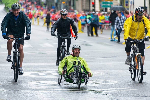 Wheelchair competitor in Madrid Marathon under heavy rain Madrid, Spain - April 26, 2015: Wheelchair competitor racing at the EDP Rock 'n' Roll Marathon in Madrid, entering the final kilometer of the race in first place surrounded by three stewards on bikes. paralympic games stock pictures, royalty-free photos & images