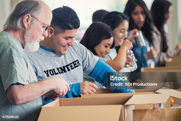 Diverse Group Of Volunteers Sorting Donated Groceries At Food Bank Stock Photo - Download Image Now