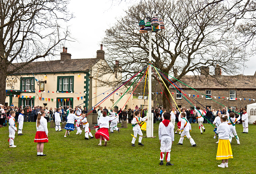 Long Preston, North Yorkshire, England- May 4, 2013: Local children dance round a traditional Maypole on the village green as part of the May Day Gala, a yearly community event.