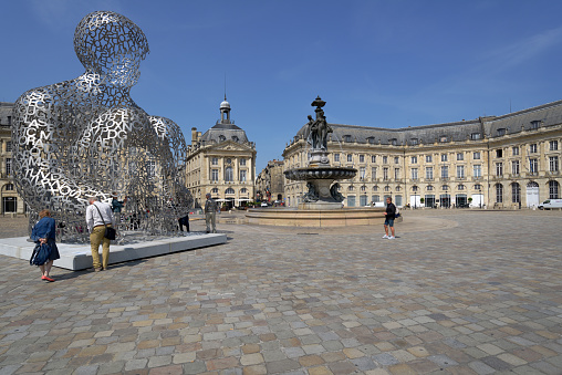 Bordeaux, France - June 27, 2013: Tourists in front of the artwork of Jaume Plensa House Of Knowledge against the Fountain of Three Grace on the Place de la Bourse. The fountain was erected in 1869