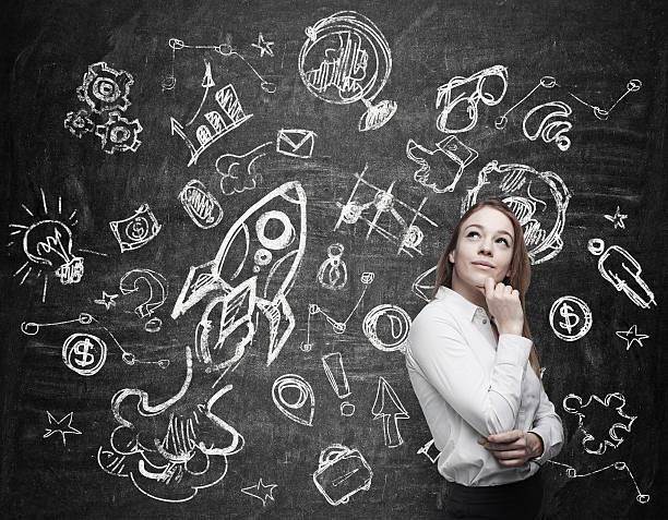 istock Young woman thinking next to chalkboard with illustrations 471509666