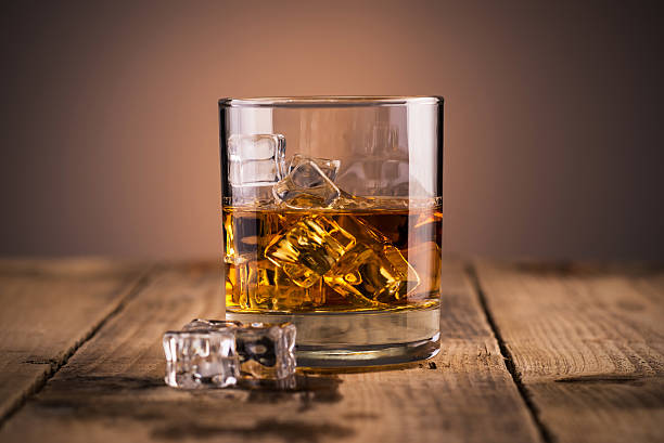 Glass of whiskey Whiskey in a glass over ice cubes, on wooden table cognac region photos stock pictures, royalty-free photos & images
