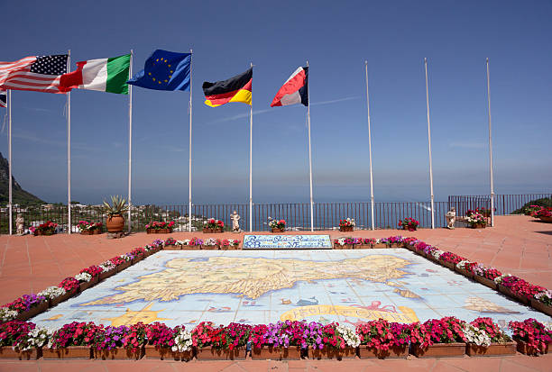 Capri Town in Campania,. Italy Marina Piccolo, Italy - May 3, 2013: The national flags of four countries fly in Capri Town over a map of Capri surrounded by flowers.  amalfi coast map stock pictures, royalty-free photos & images