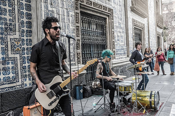 Mexico city, Mexico - December 20, 2014: Picture of a group of rock musicians performing live in the streets of Mexico city. The picture was taken at the side of the 'Casa de los Azulejos' palace, where a Sanborns restaurant is located. The performers where surrounded by local people while they sang and played their instruments to the sound of punk rock music. A stank of marihuana was perceived in the environment.