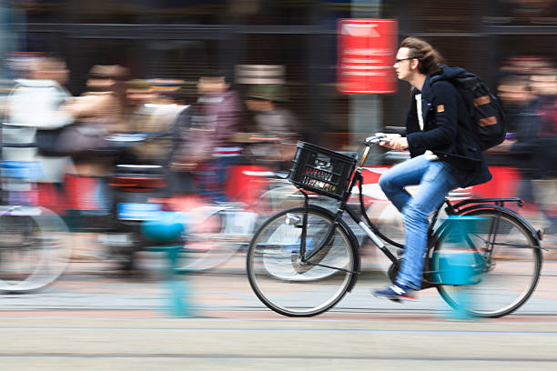 man riding a bicycle down the street stock photo