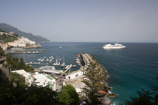 Amalfi, Italy - April 30, 2013: A wide-angle view of Amalfi beachfront, including a cruise liner in the background and several bathers enjoying the spring sunshine. 
