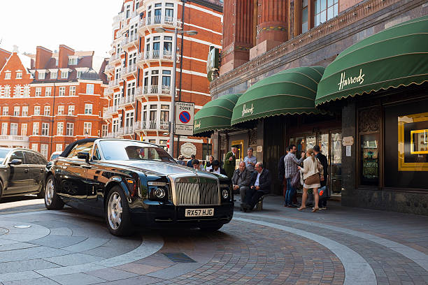 Rolls Royce parked in front of Harrods London, United Kingdom - May 3, 2013: A black Rolls Royce is parked in front of Harrods, the upmarket department store in London, United Kingdom. A Harrods doorman in it's famous green uniform is talking to a man while other people are chatting or just passing by. Harrods is famous for its quality & luxury goods. harrods photos stock pictures, royalty-free photos & images