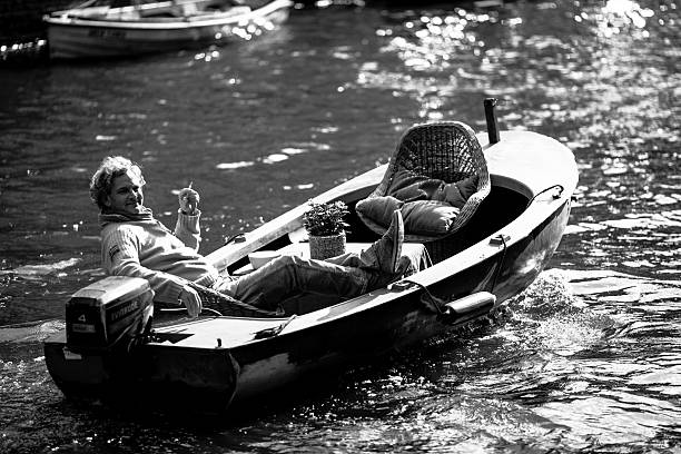 Smiling man on boat driving with one hand and smoking stock photo