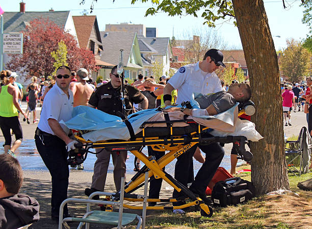 Man Being Treated for Exhaustion by EMTs Bloomsday 2013 Spokane, USA - May 5, 2013. Runner being treated for exhaustion by EMTs during Bloomsday, an annual timed road race held on the first Sunday of every May. bloomsday stock pictures, royalty-free photos & images