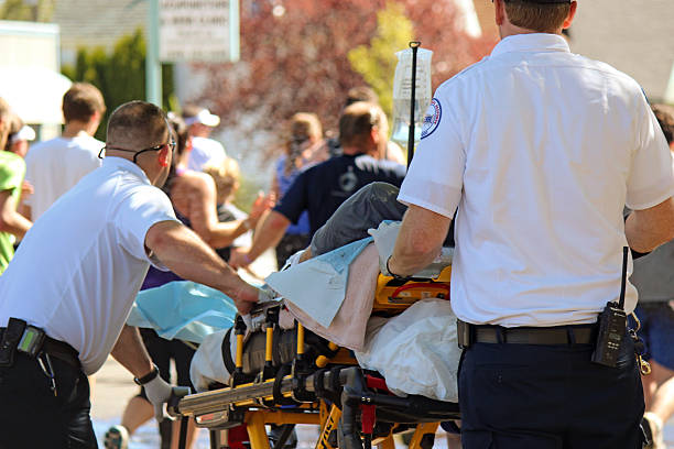 Man Being Treated for Exhaustion by EMTs Bloomsday 2013 Spokane, USA - May 5, 2013: Runner being treated for exhaustion by EMTs during Bloomsday, an annual timed road race held on the first Sunday of every May. bloomsday stock pictures, royalty-free photos & images