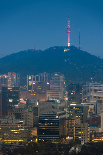 Seoul, Korea - 27th April 2013: The iconic spire of the N Seoul Tower illuminated colourfully high on Namsan mountain park overlooking the crowded skyscraper cityscape shining in the heart of downtown Seoul, South Korea.