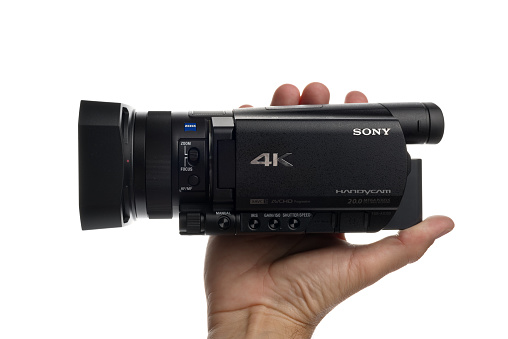 Novi Sad, Serbia - April 25, 2015: Person holding Sony FDR AX100, 4k UHD Handycam Camcorder captures Ultra High Definition Footage. Illustrative editorial for product isolated on white background.