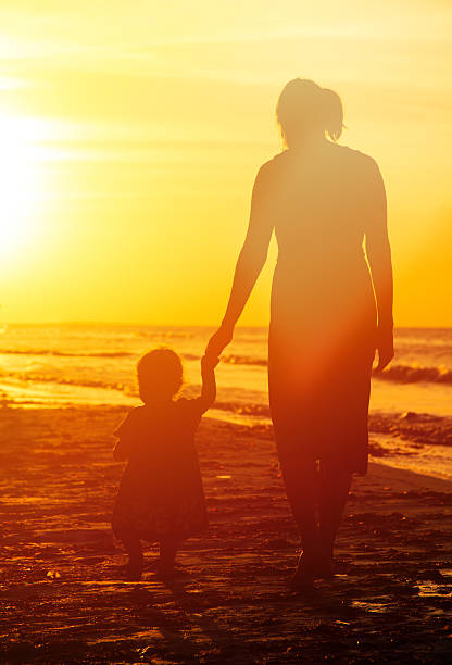 istock mother and little daughter walking at sunset 471514832